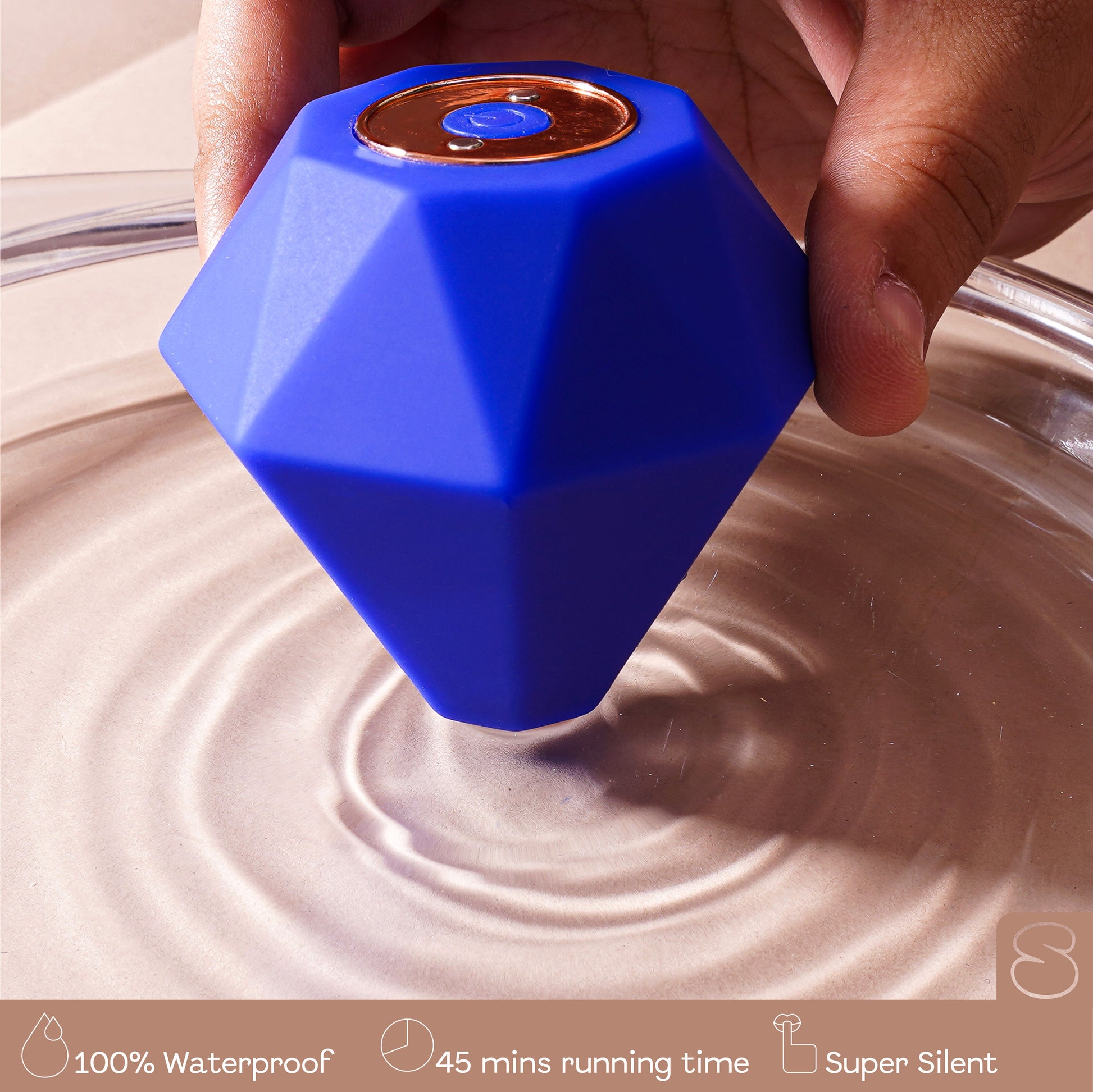 Blue diamond massager creating ripples in water while held by hand, highlighting waterproof feature