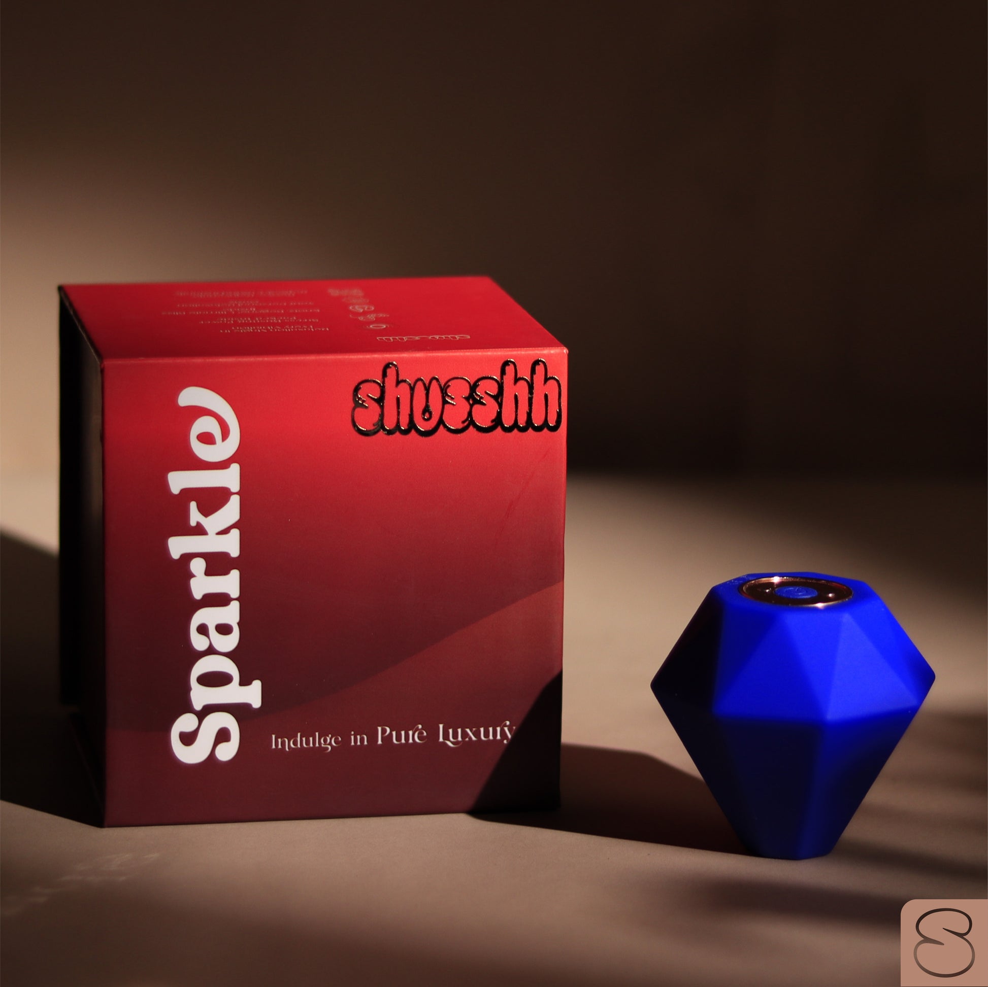 Blue Sparkle massager placed beside red Shusshh branded packaging on a minimal beige background