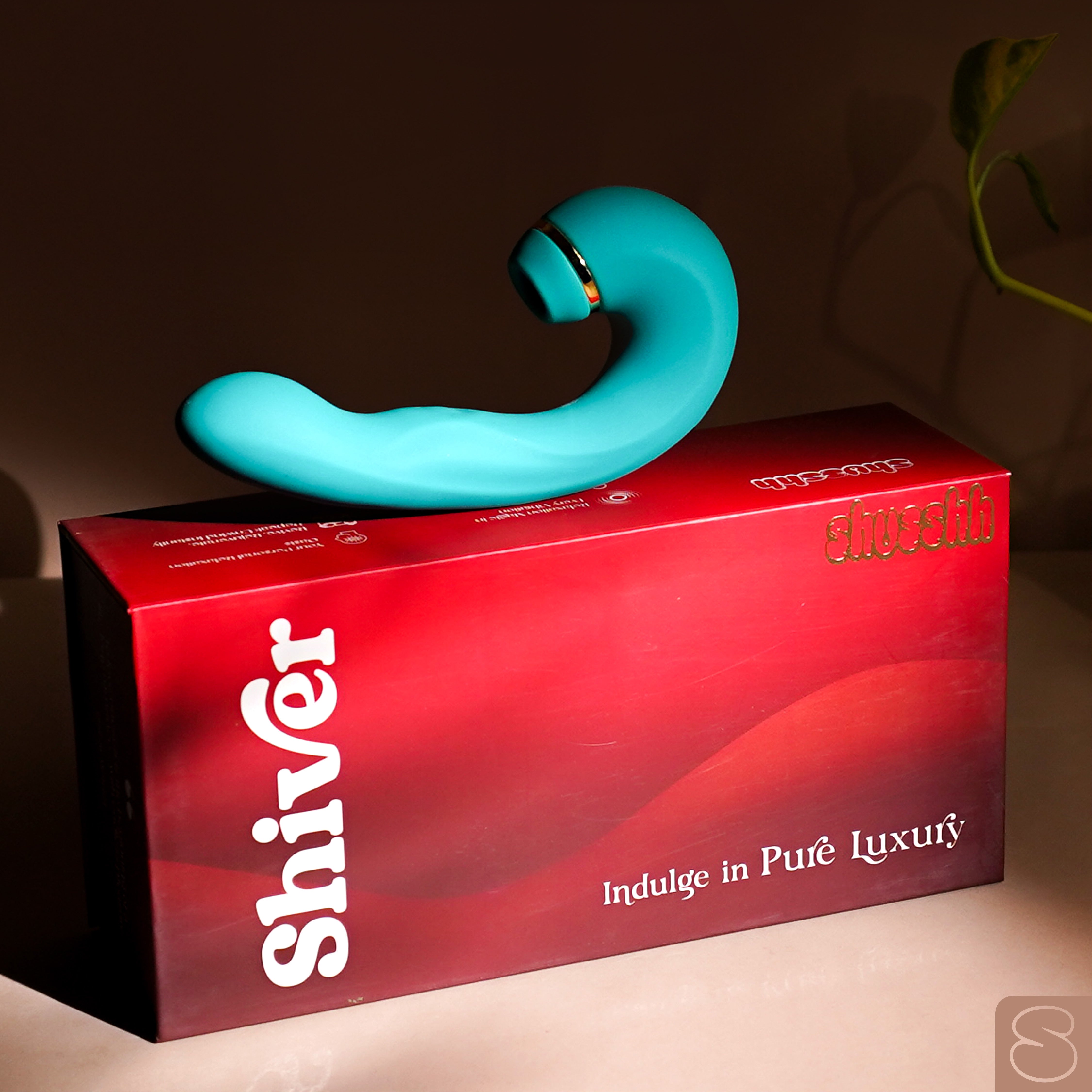 Shiver massager placed stylishly on a deep red box with gold branding and luxury text