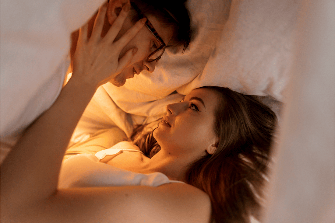 A couple enjoying an intimate moment in bed, gazing at each other with tenderness and connection, representing the importance of communication, trust, and emotional connection for lasting intimacy.