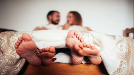 How to know if a guy is a virgin – A blurred couple in bed with their feet visible under the covers, symbolizing intimacy and relationships.